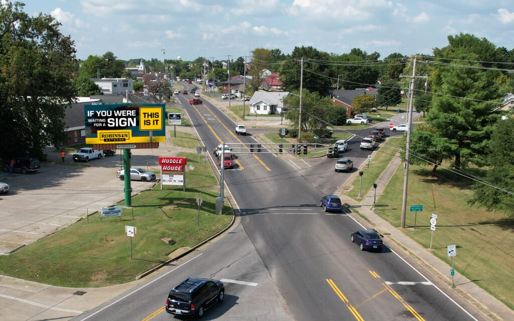 A view of an intersection with cars driving down the road.