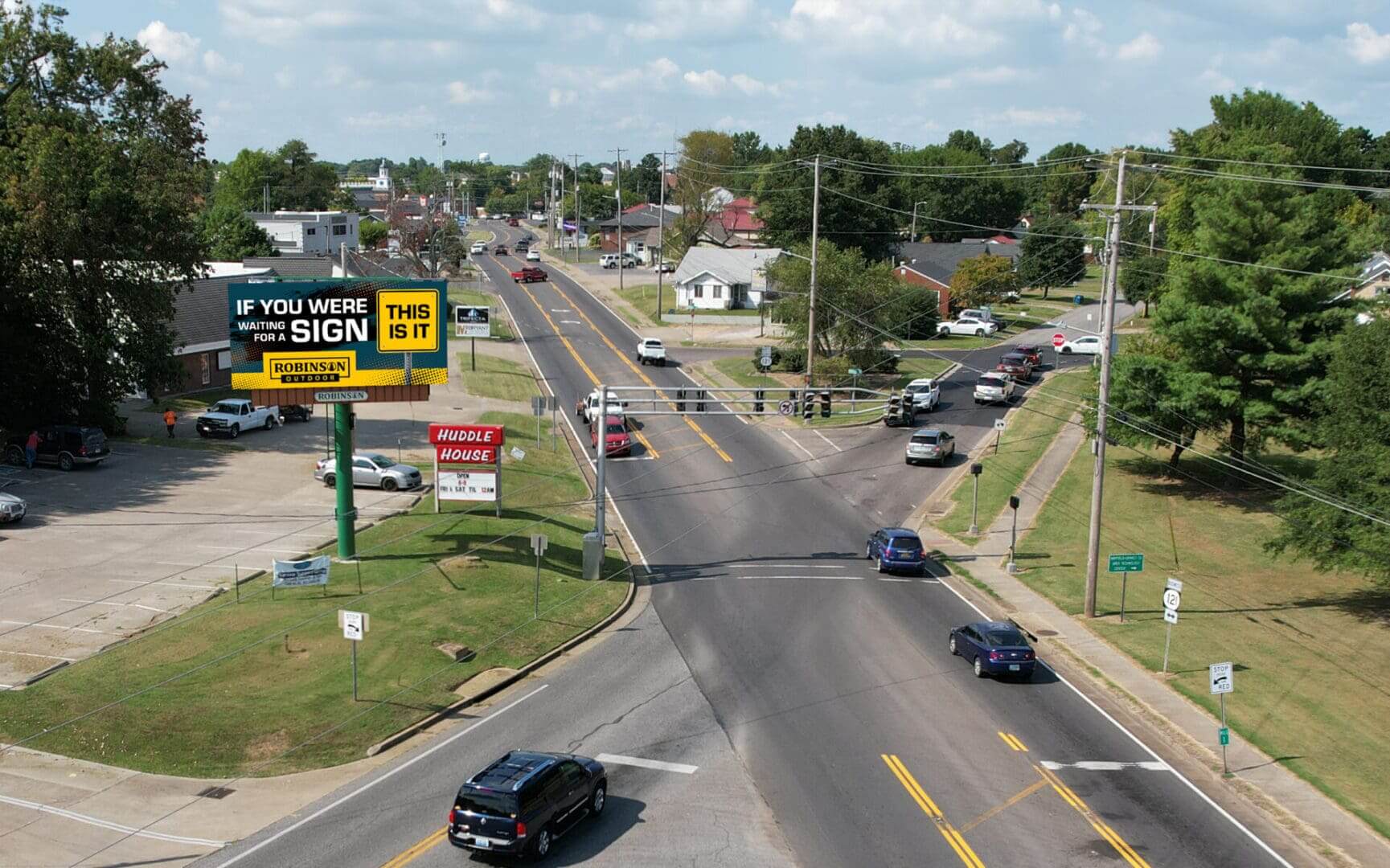 A view of an intersection with cars driving down the road.