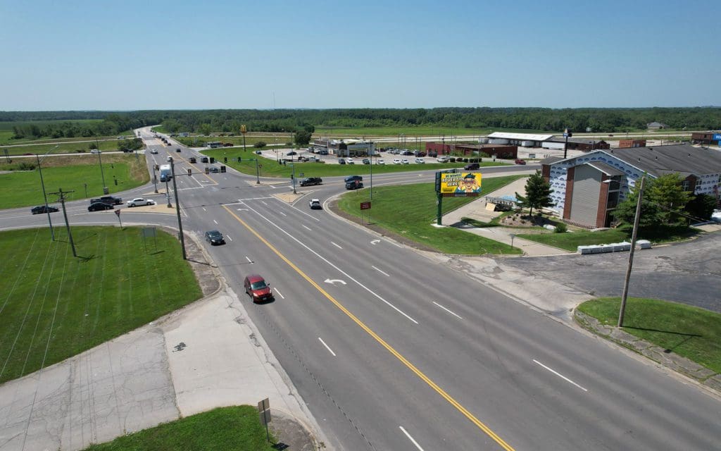 A view of an intersection with cars driving down the road.