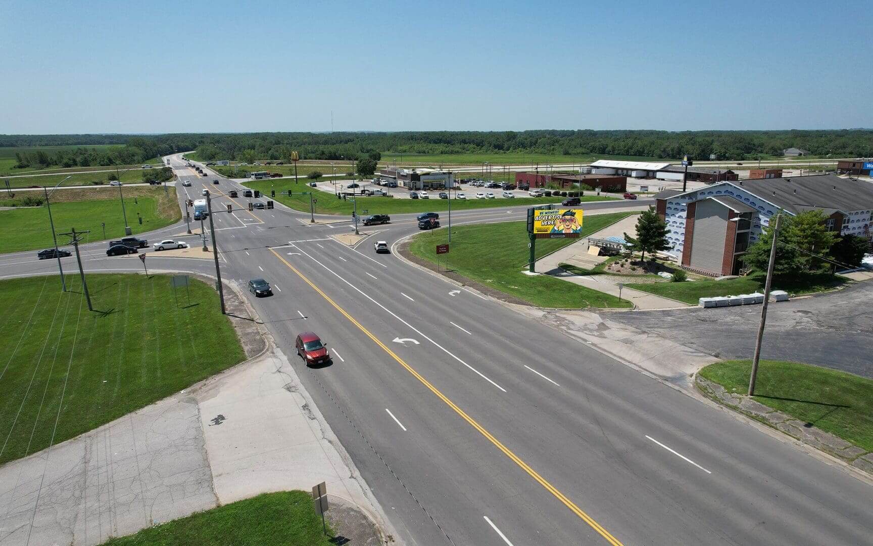 A view of an intersection with cars driving down the road.