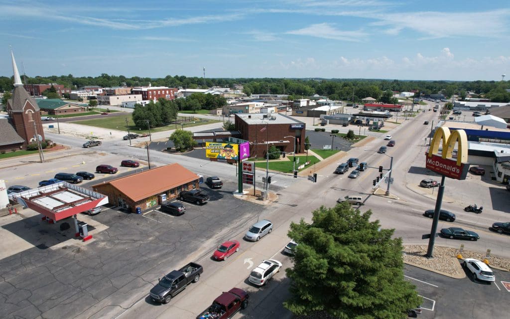 A view of an intersection with cars driving down the road.