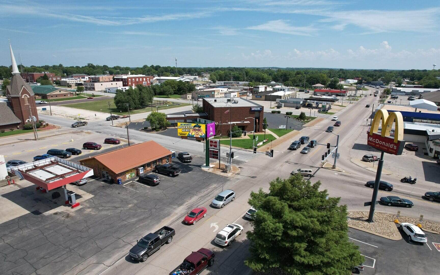 A view of an intersection with cars driving down the road.