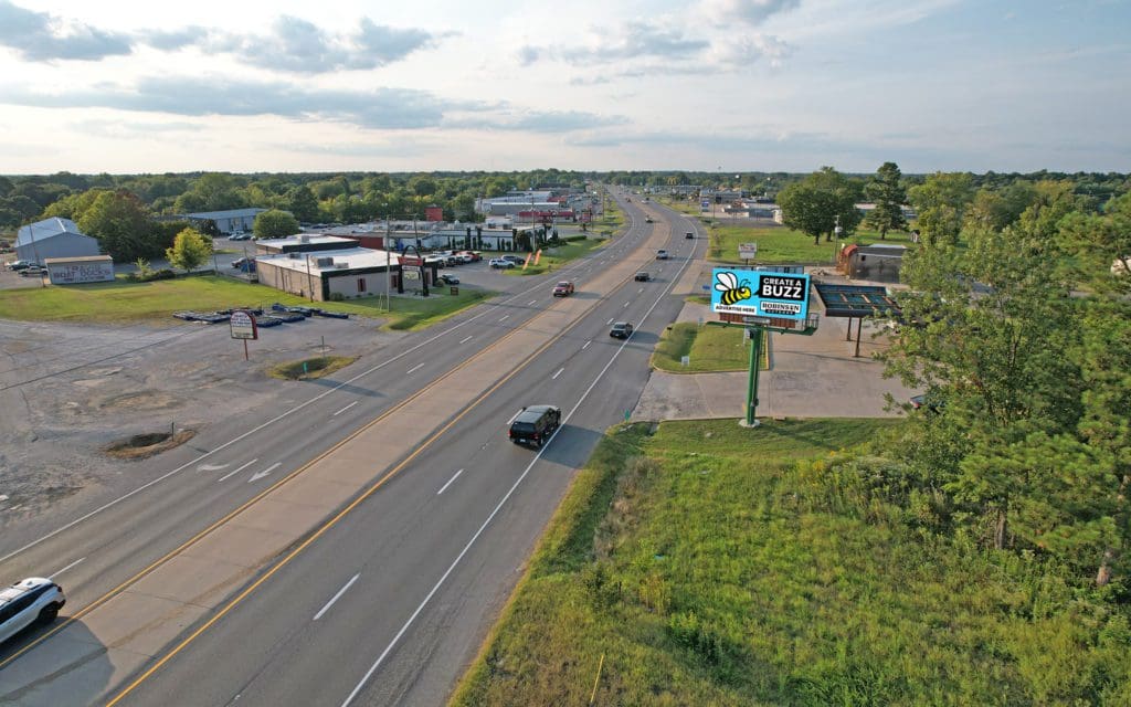 A highway with cars driving down it and buildings in the background.