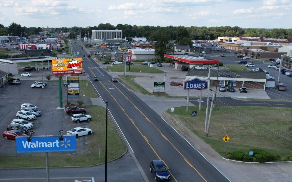 A view of an intersection with cars driving down the road.