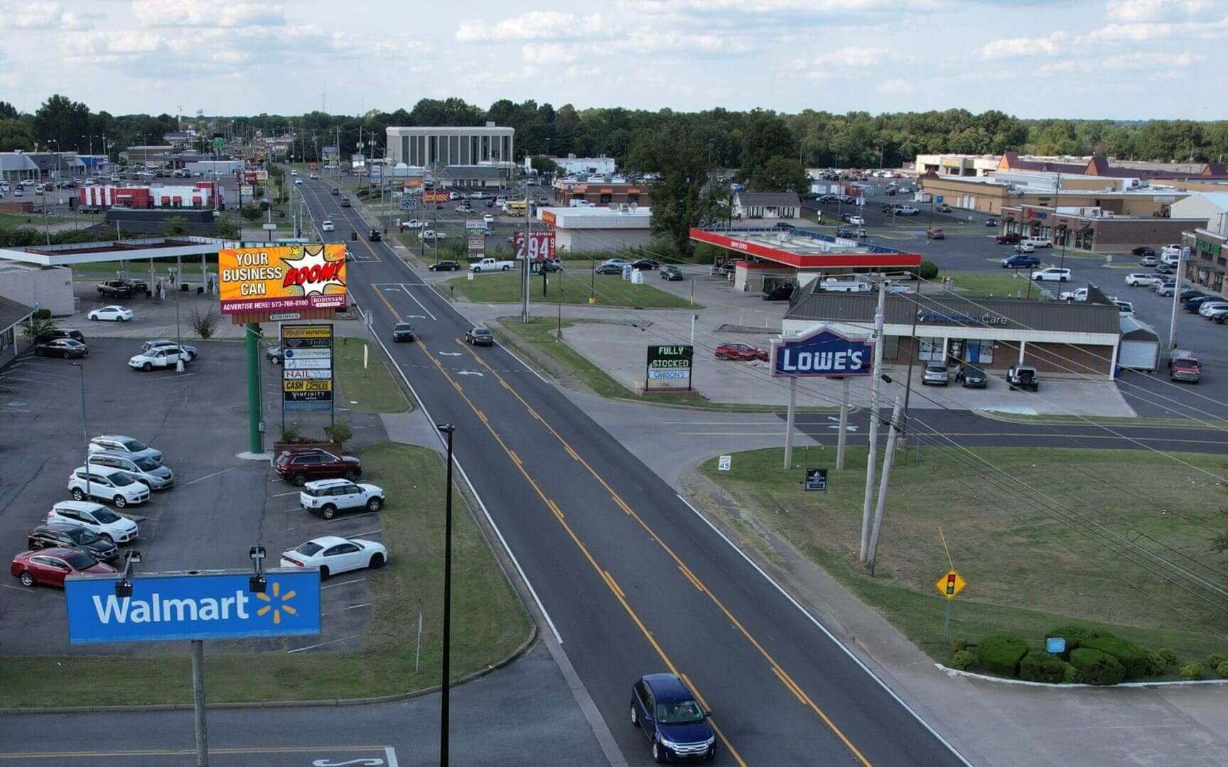 A view of an intersection with cars driving down the road.