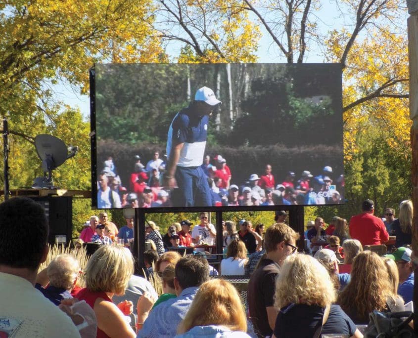 A crowd of people watching an outdoor movie.