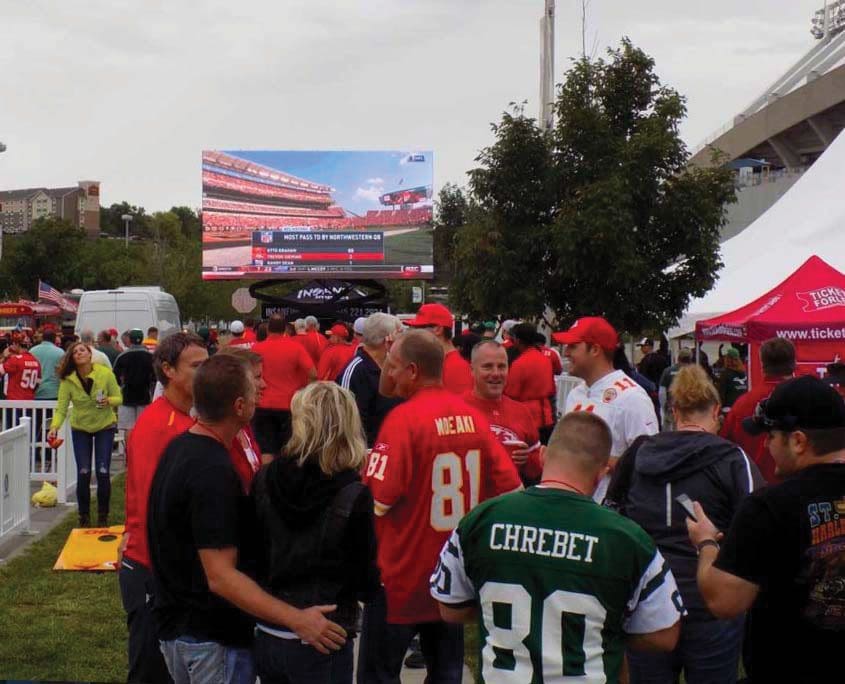 A group of people standing around in the grass.