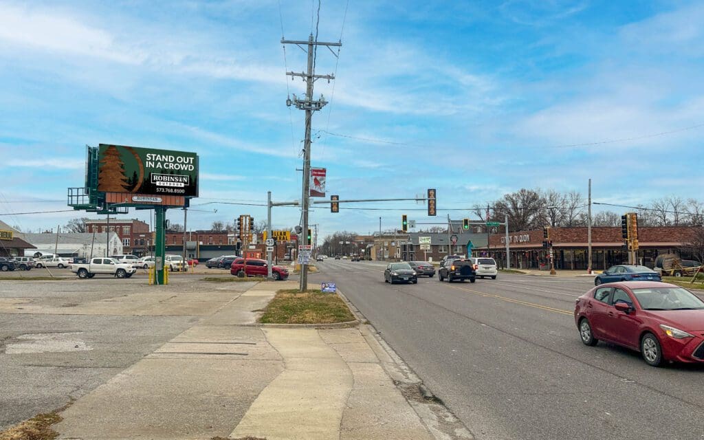 A street with cars driving down it and a traffic light.