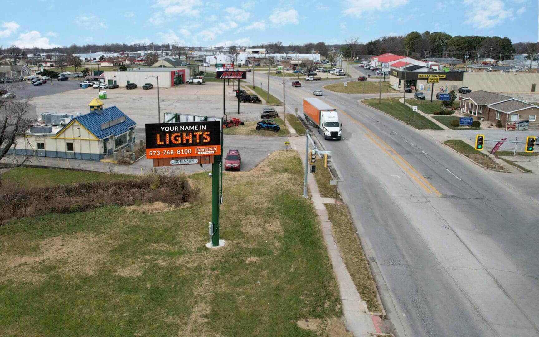 A view of an intersection with cars driving down the road.