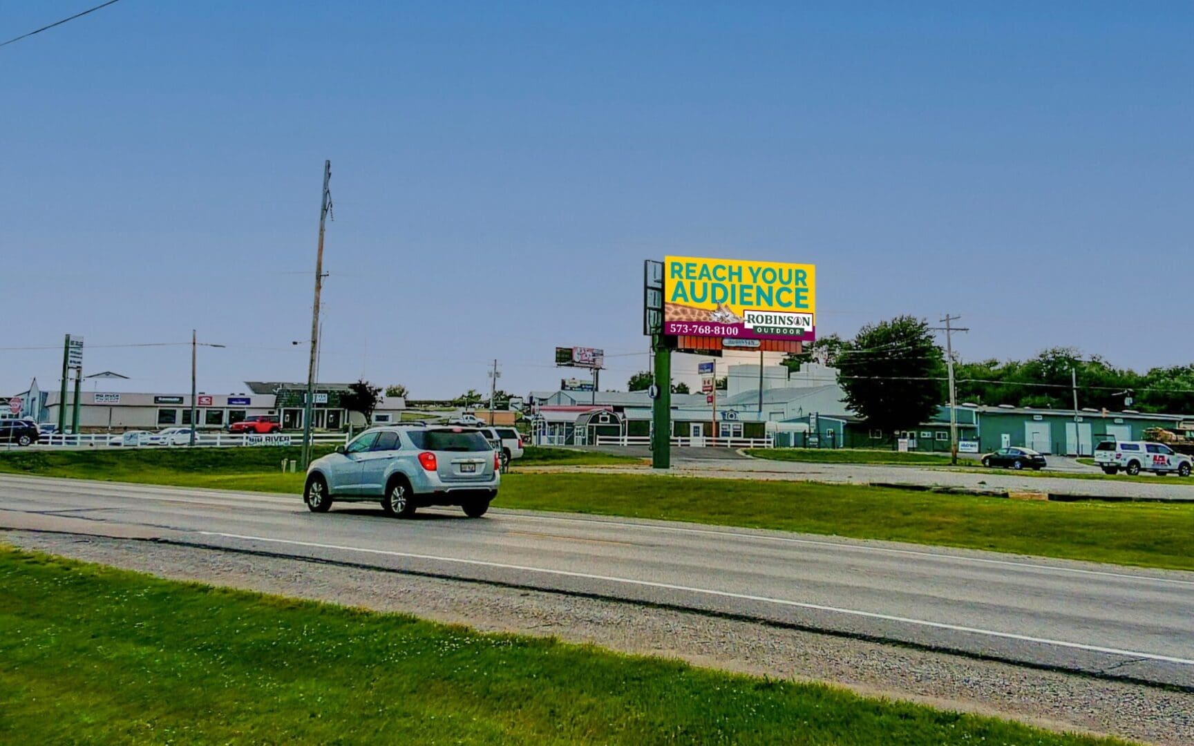 A car driving down the road with a billboard on it.