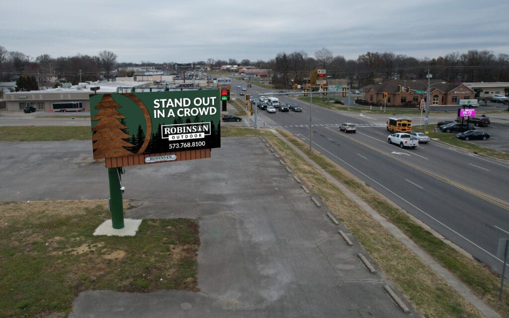A billboard on the side of a road with trees.