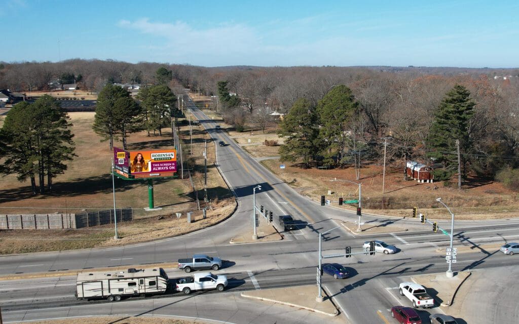 A view of an intersection with cars driving on it.