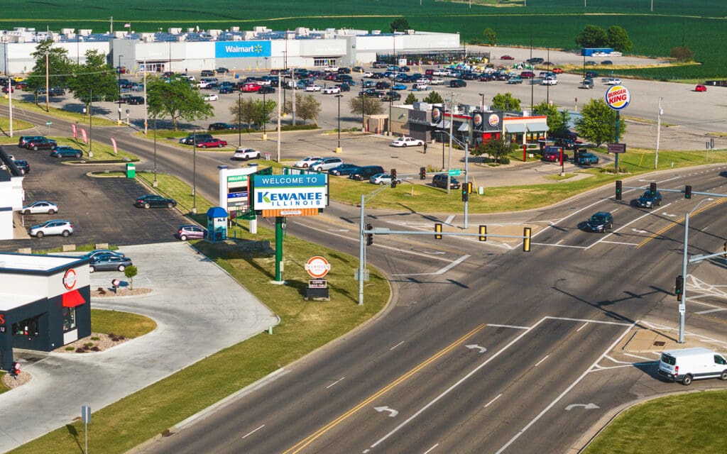 A view of an intersection with cars parked on the side.