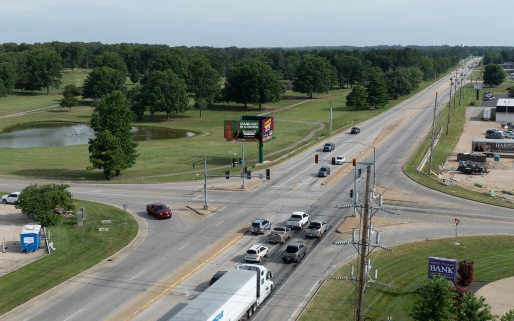 A highway with cars driving on it and trees in the background.