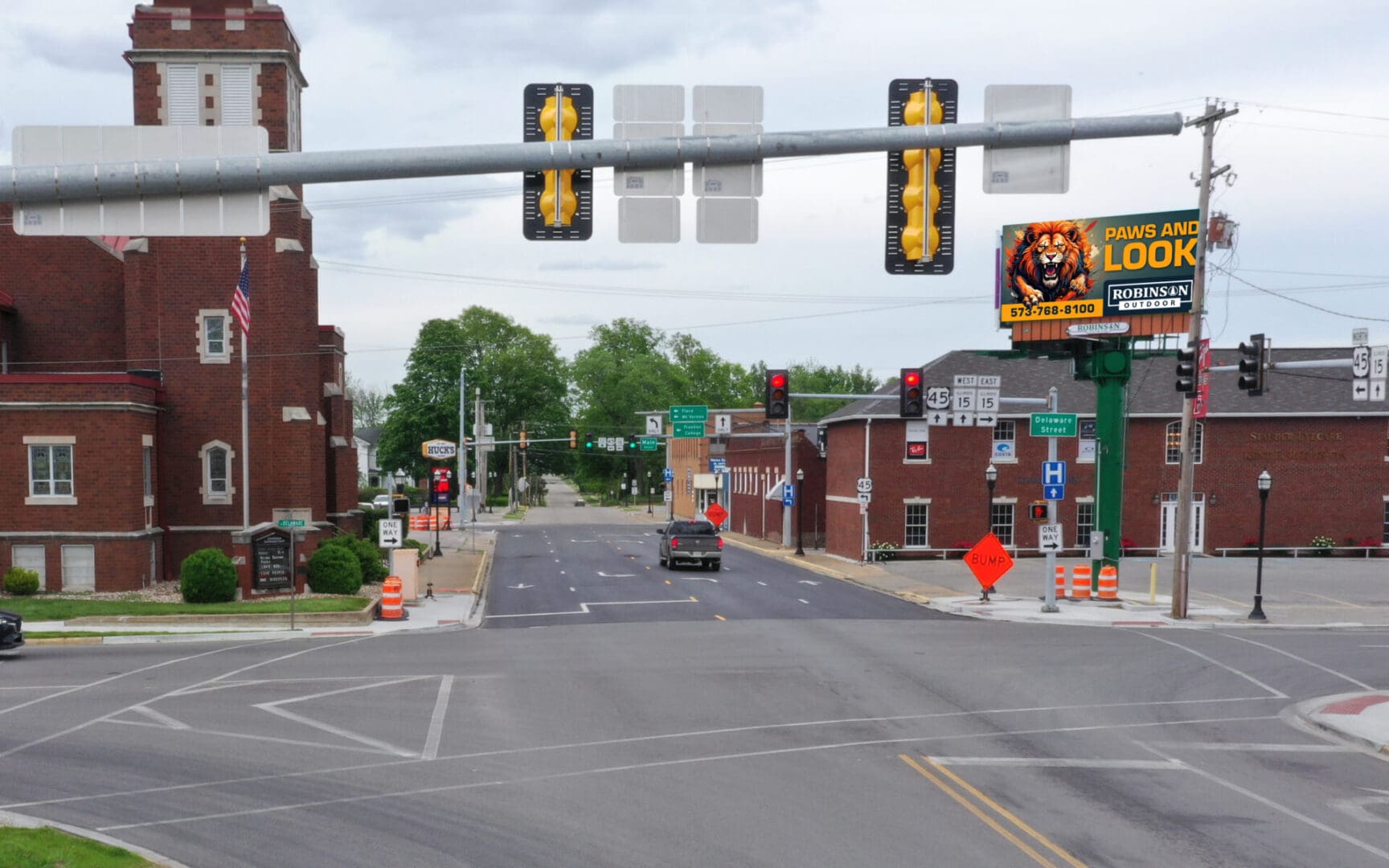A quiet urban street with traffic lights and brick buildings on both sides.