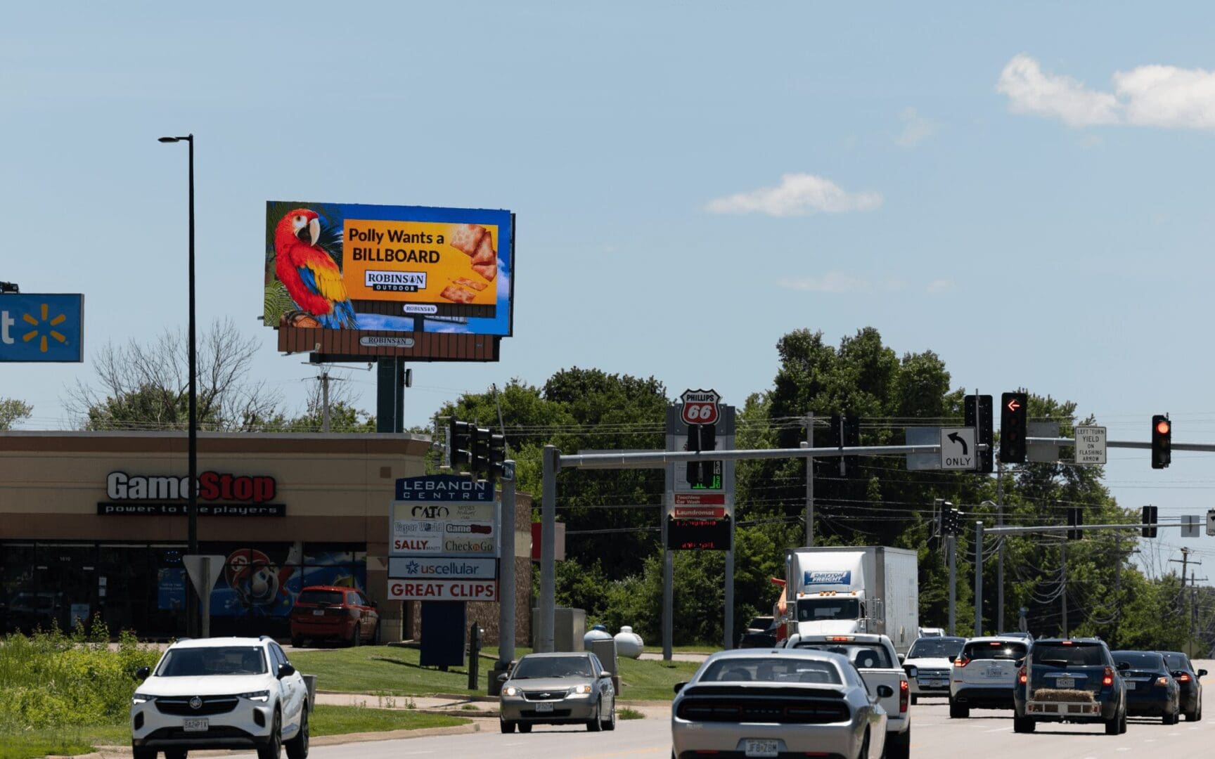 A busy street with cars and billboards on the side.