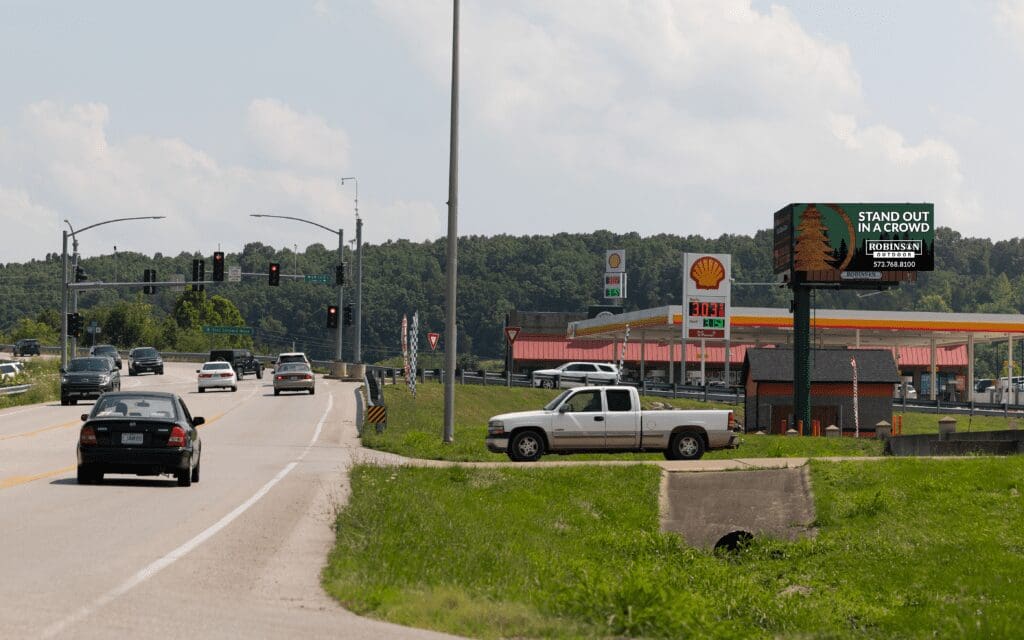 A truck is driving down the road near gas stations.