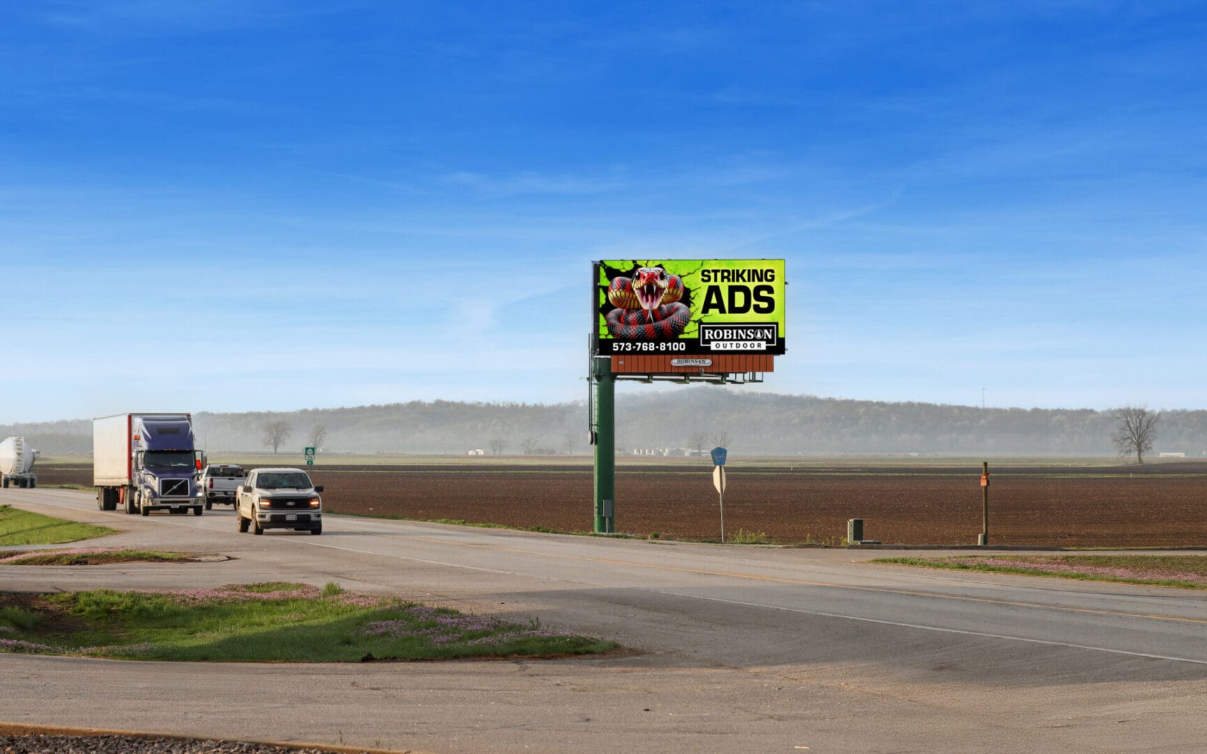 A billboard on the side of a road with a truck driving by.