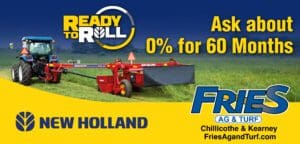 A red tractor is in the grass with a trailer.