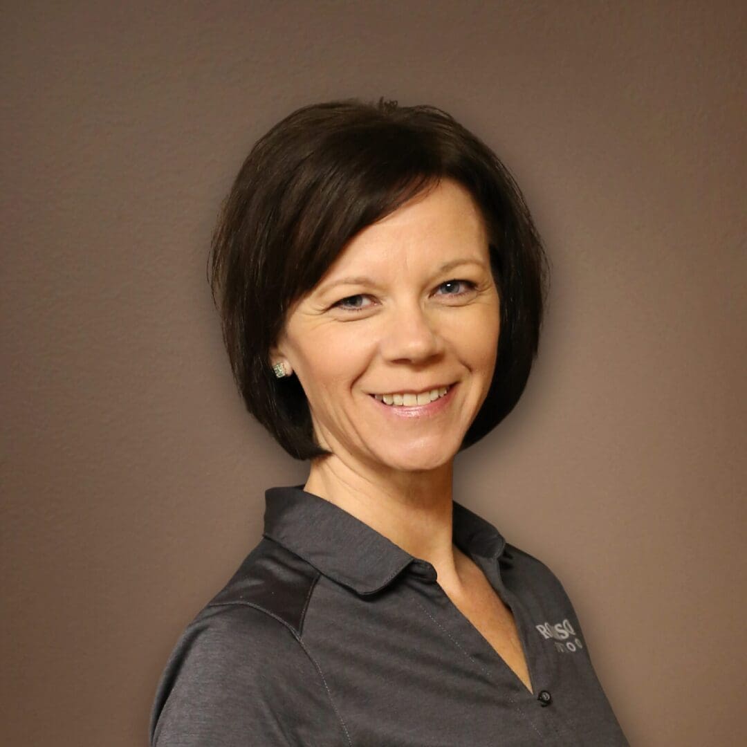 A woman standing in front of a brown wall.