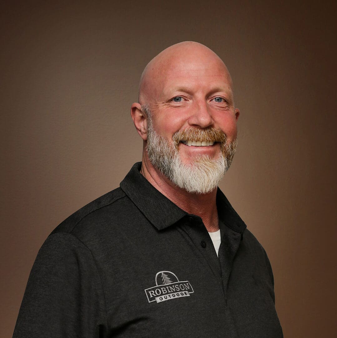 Smiling bald man with gray beard, black polo