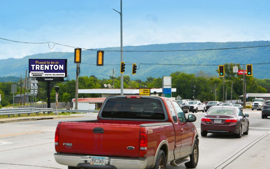 Red pickup truck at intersection with billboard