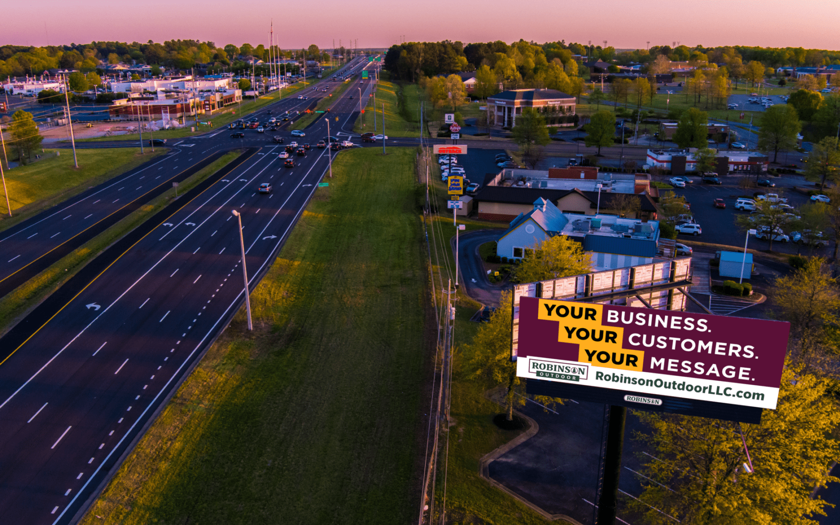 Aerial highway at sunset with roadside billboard